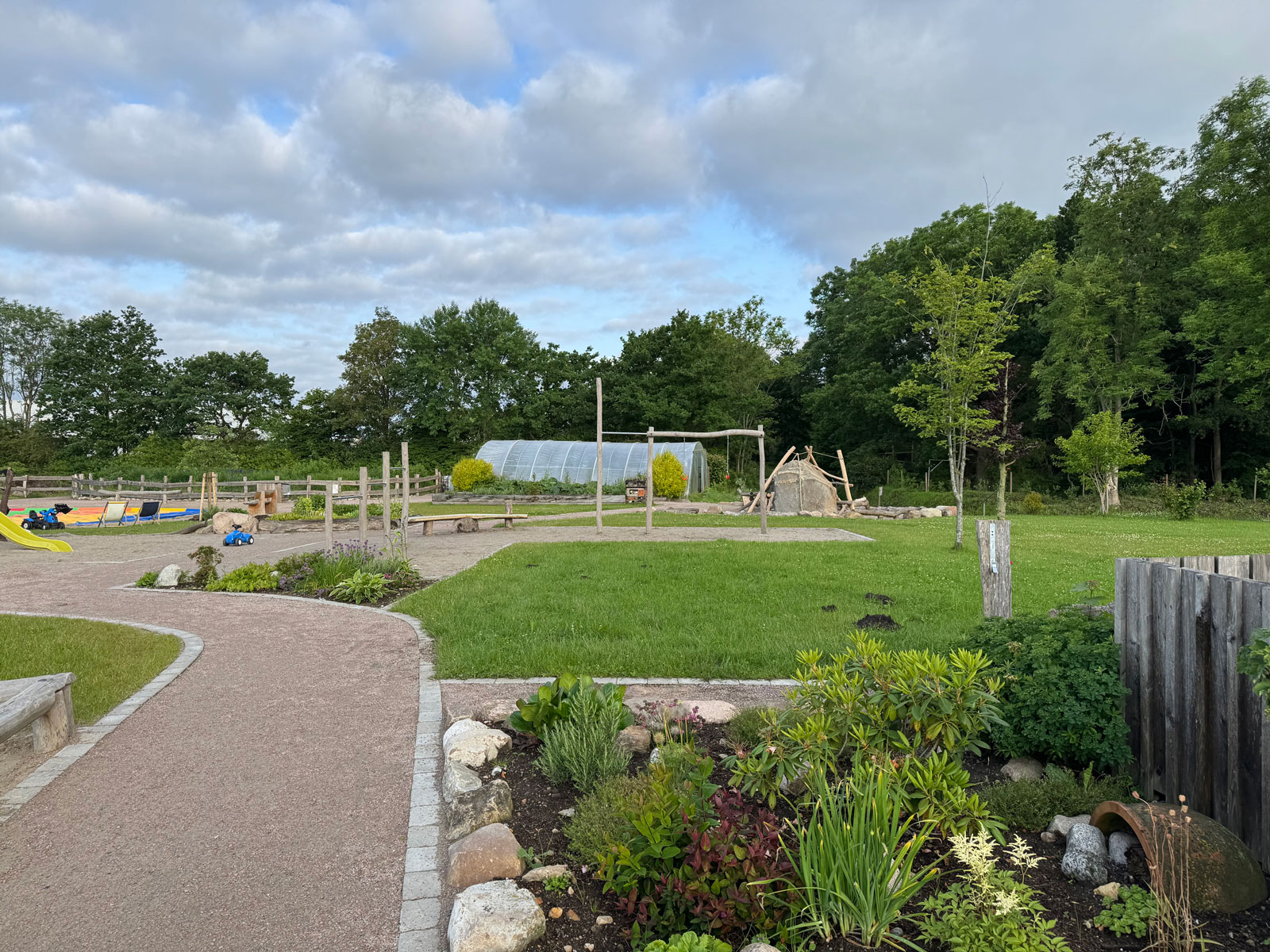 Spielplatz auf dem Biohof Backensholz mit Holzspielgeräten und Garten